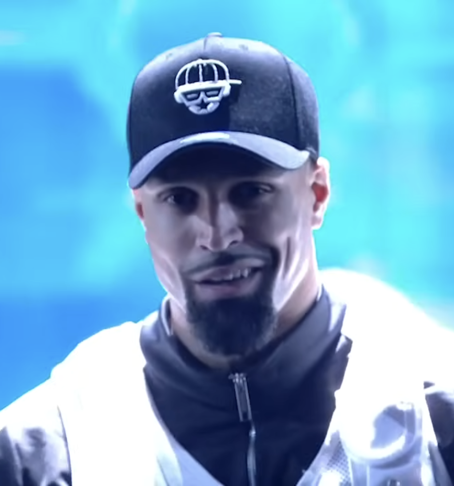 Diversity dancer in a black cap smiling on a blue-lit stage